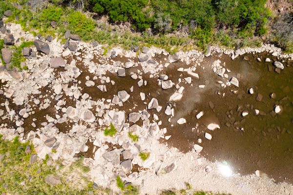 Bird's eye view of river flowing through rocks and vegetation