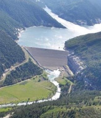 Bird's eye view of a reservoir, dam, and river below