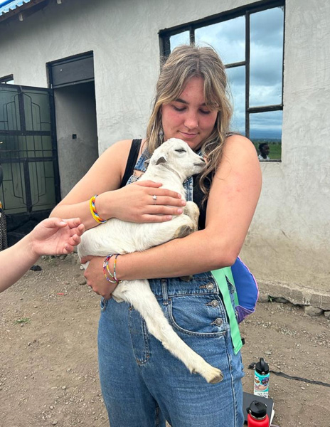 A woman holding a baby goat