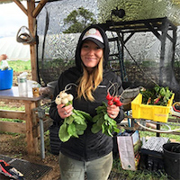 Girl holding radishes at a farm stand